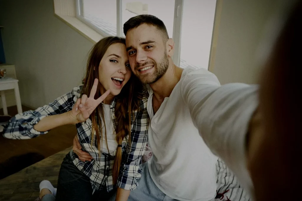 Junges Paar macht glücklich ein gemeinsames Selfie und wirkt verliebt und unbeschwert.
