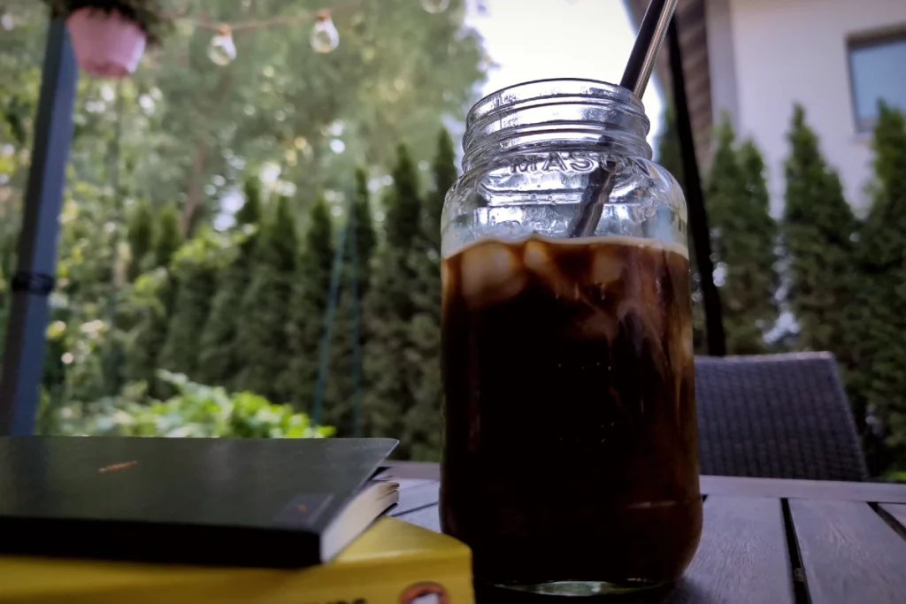 Selbst gemachter Cold Brew Coffee mit Eiswürfeln auf dem Gartentisch an einem warmen Sommertag.