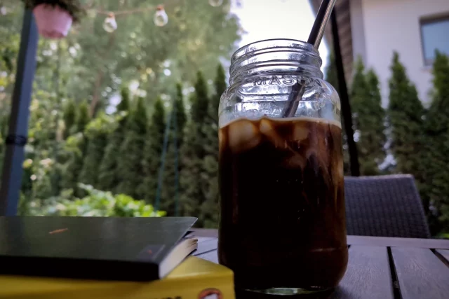 Selbst gemachter Cold Brew Coffee mit Eiswürfeln auf dem Gartentisch an einem warmen Sommertag.