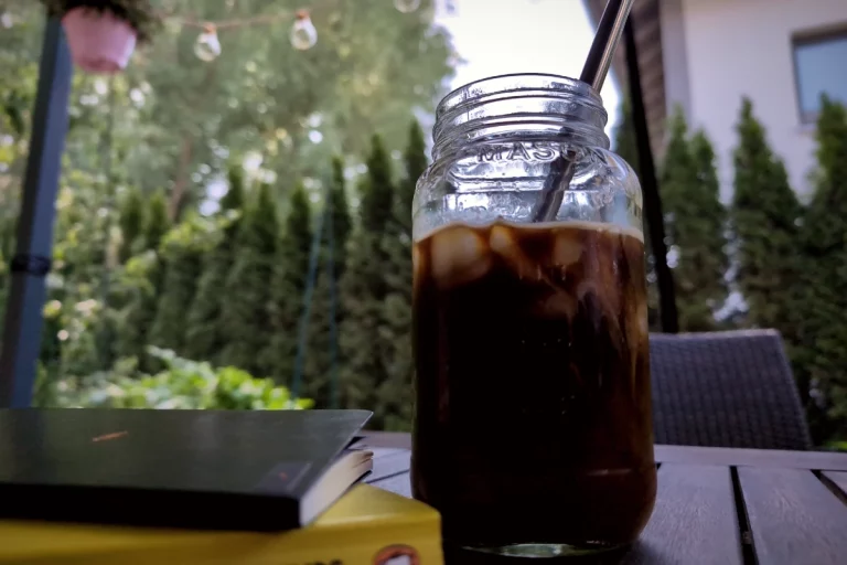 Selbst gemachter Cold Brew Coffee mit Eiswürfeln auf dem Gartentisch an einem warmen Sommertag.