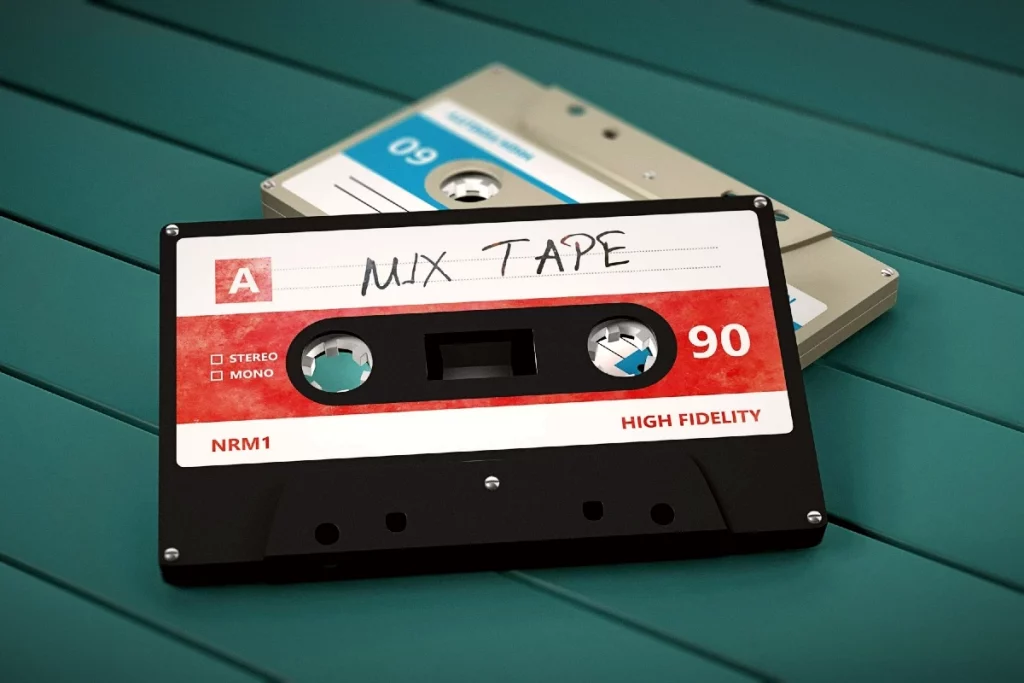 Zwei Audiokassetten liegen auf einer türkisfarbenen Holzfläche, die obere handbeschriftet mit dem Wort Mix Tape.