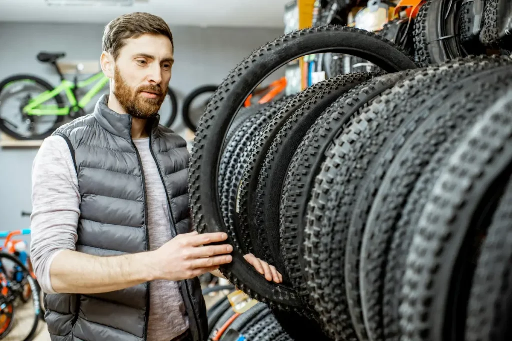 Mann betrachtet Fahrradreifen im Geschäft – Ausrüstung kaufen ersetzt oft nicht das eigentliche Hobby.