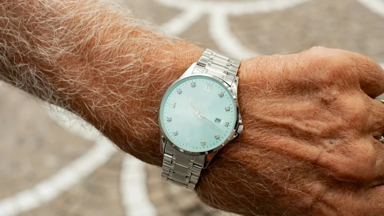 Älterer Mann mit silberner Armbanduhr am Handgelenk.