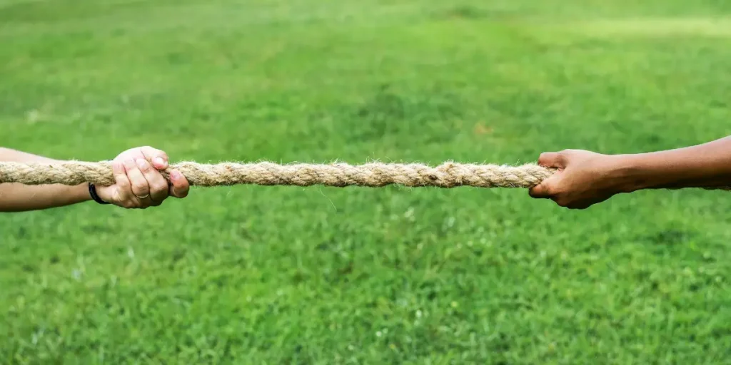 Zwei Hände greifen ein dickes Tauziehseil