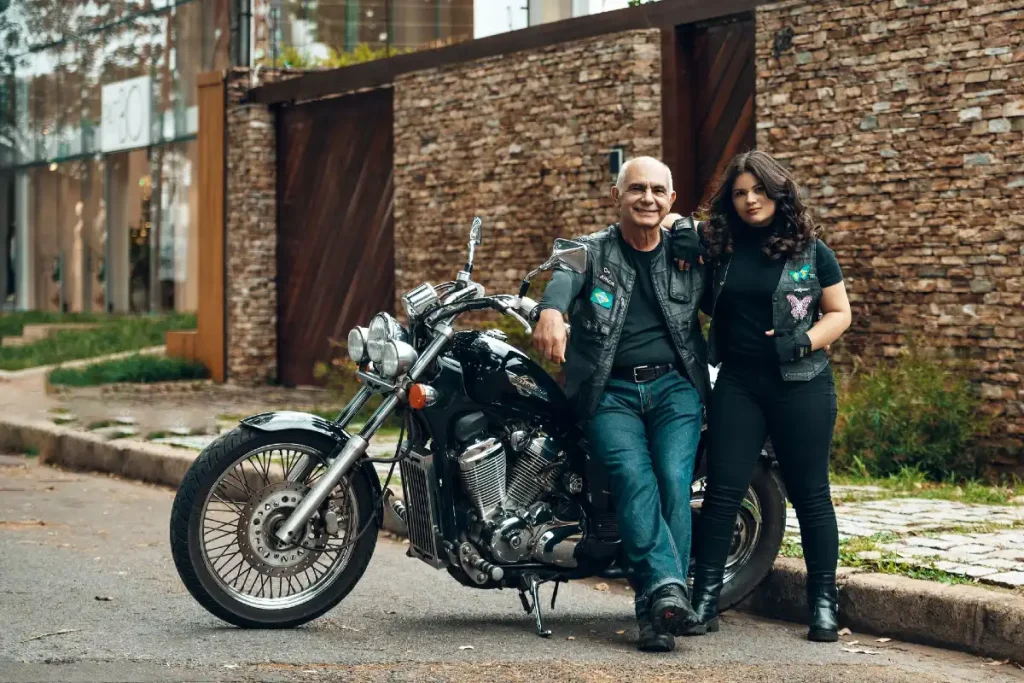 Vater und jugendliche Tochter stehen gemeinsam neben einem Motorrad.