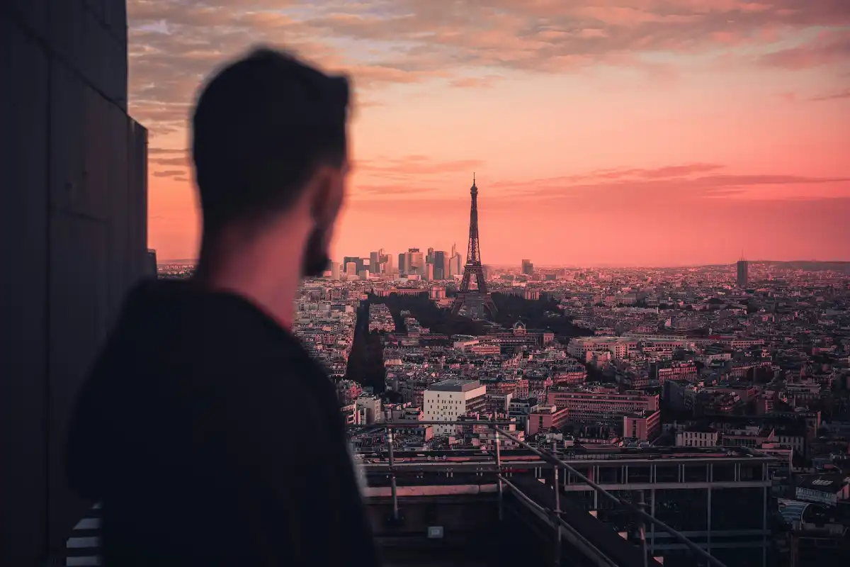 Ein Mann blickt von höher Position auf Paris, der Eiffelturm ist im Hintergrund zu sehen