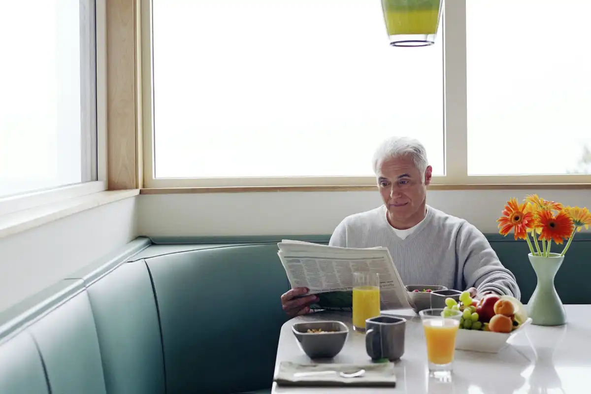 Mann liest beim Frühstück entspannt die Zeitung