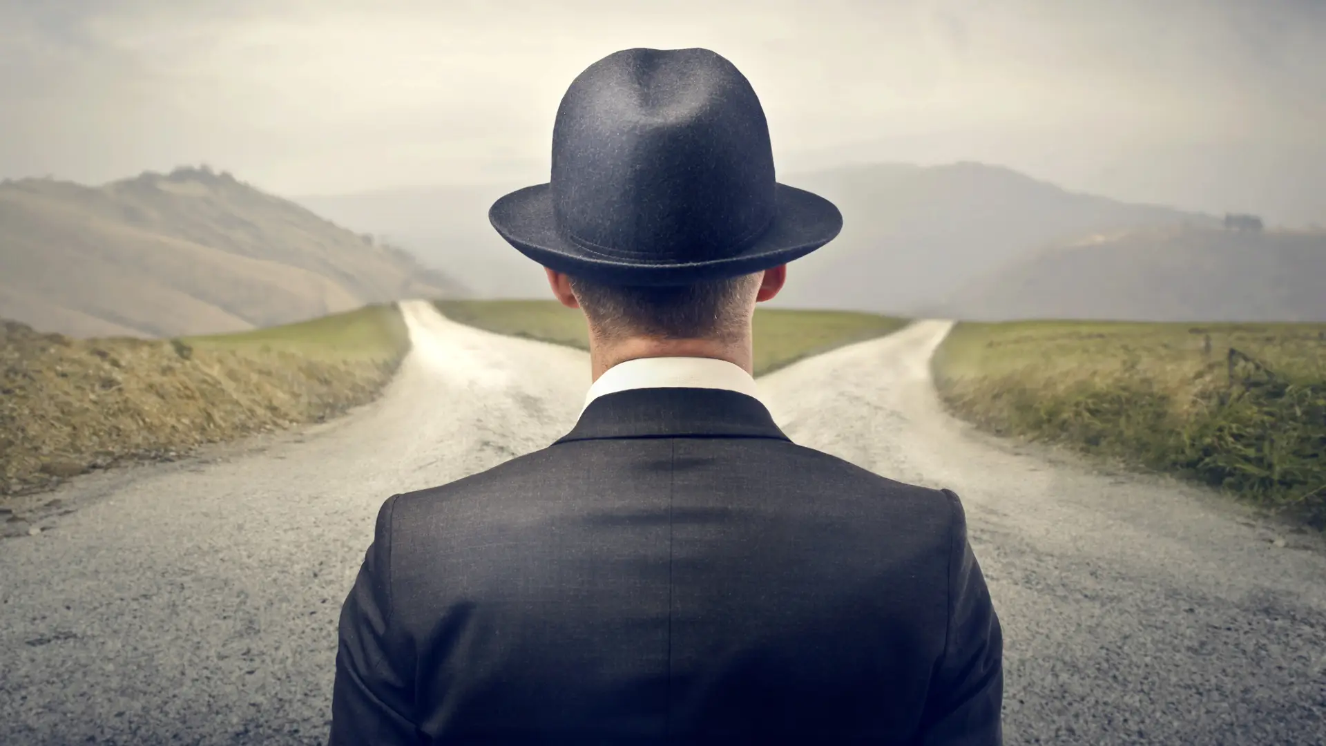 Mann mit Hut zwischen zwei Wegen